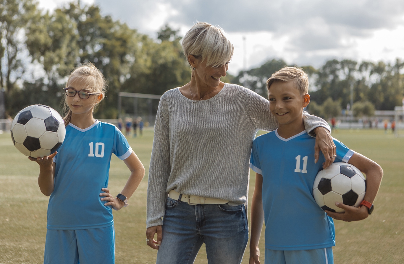 A mom with her two kids in soccer uniforms.