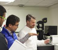 researchers discussing use of microscope